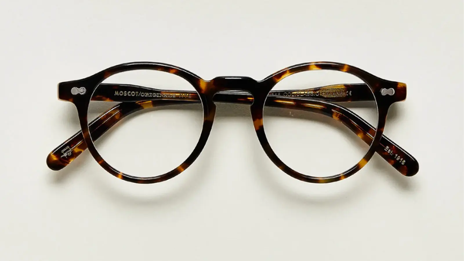 Timothée Chalamet wearing rimless Numont-style spectacles with magnified lenses and a thin silver bridge, a signature accessory for his character Marty Mauser.