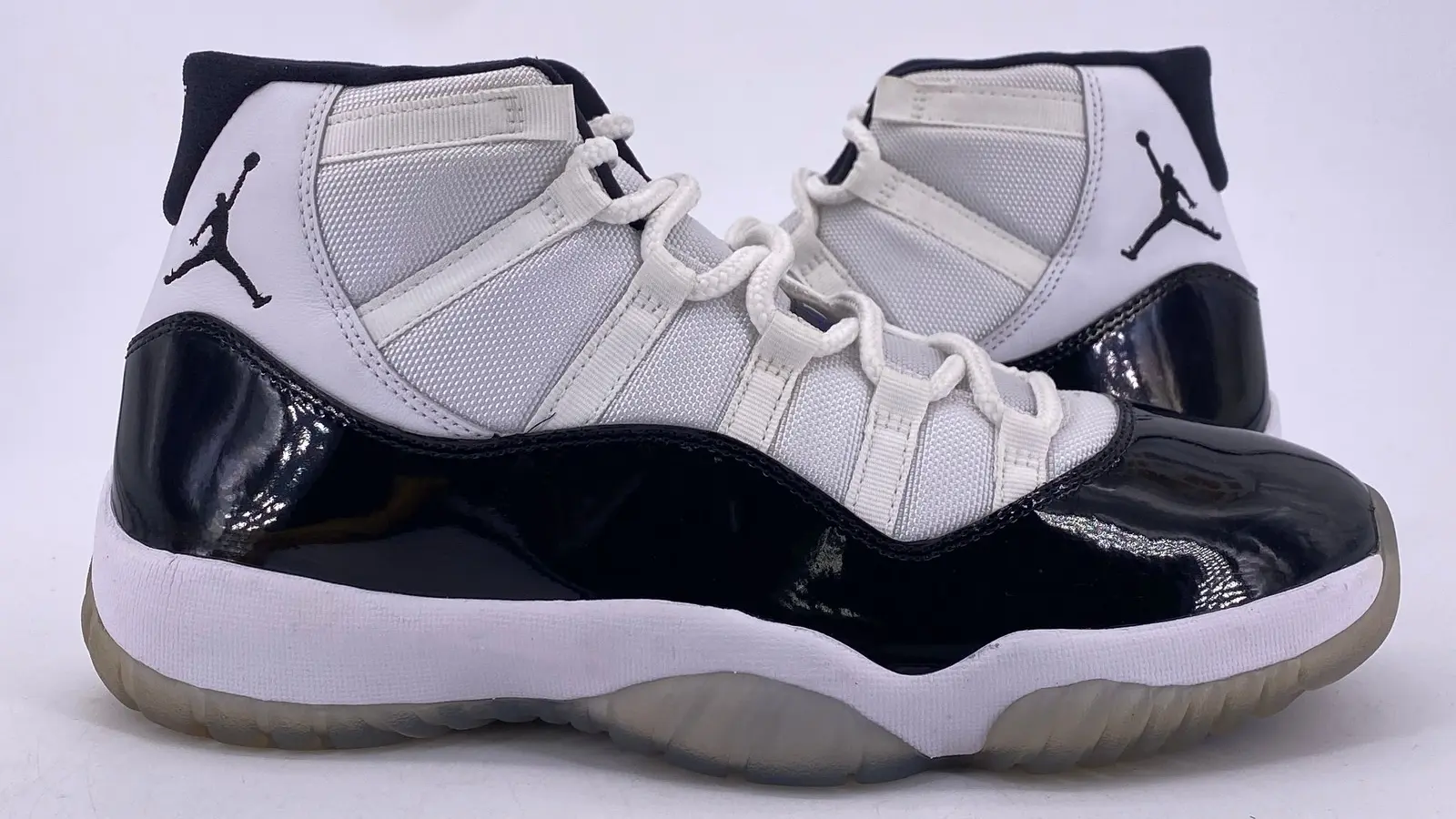 Close-up of the Air Jordan 11 Concord sneaker featuring black patent leather and white ballistic nylon with clear ice sole.