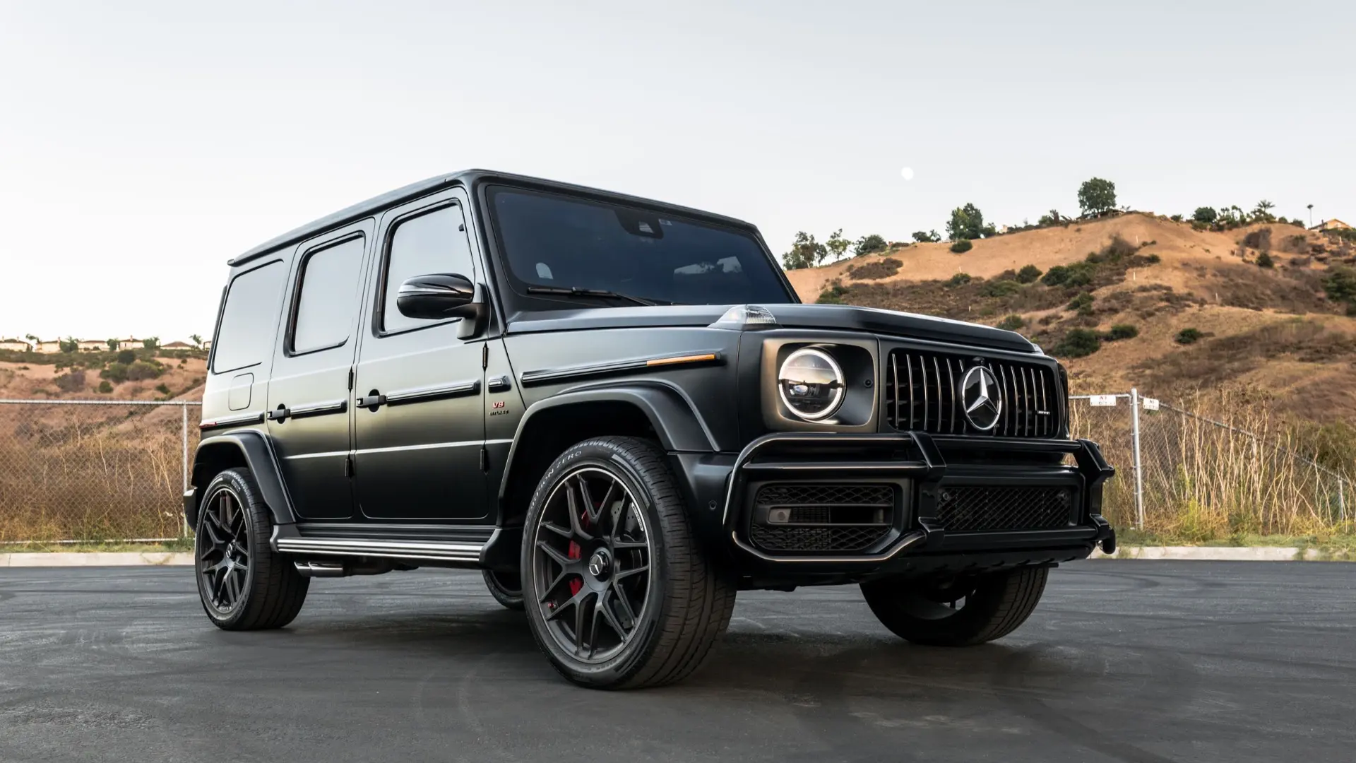 Green Mercedes-Benz G-Wagon parked on a city street, highlighting its boxy silhouette and luxury design.