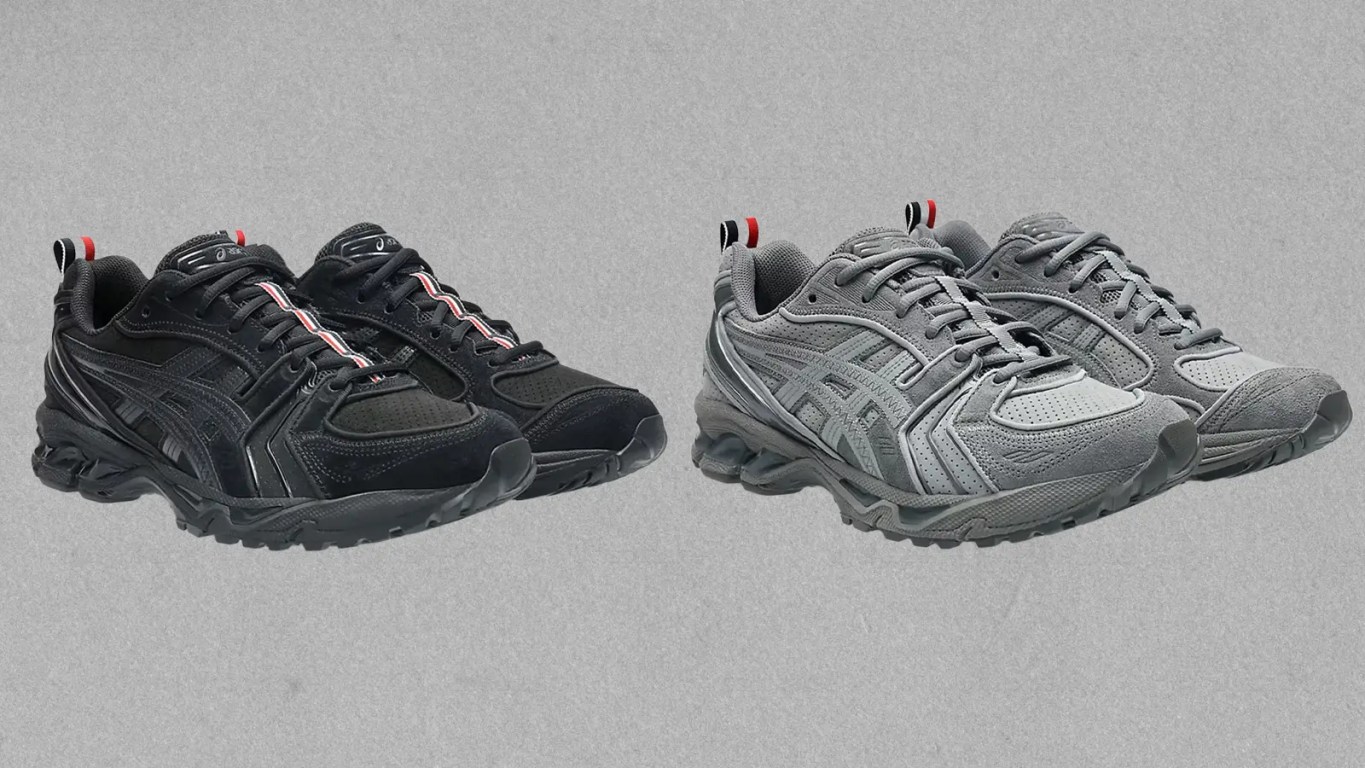 A high-fidelity studio shot of the Thom Browne x ASICS Gel-Kayano 14 in signature grey and black. The sneaker features premium suede overlays, zig-zag stitching on the side logo, and the iconic tricolor grosgrain pull tab on the heel, representing the intersection of American tailoring and Japanese performance hardware.