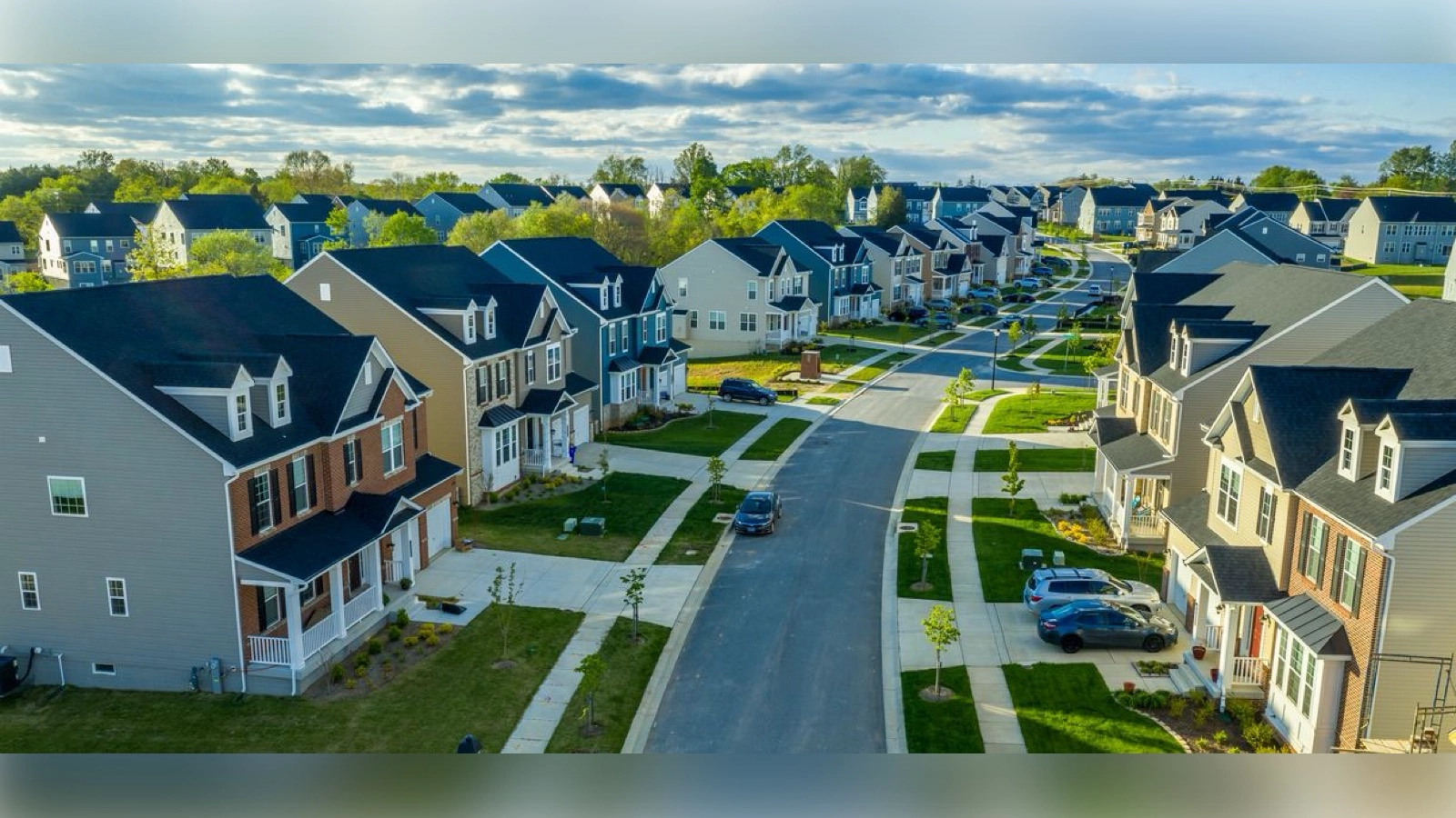 A wealthy American neighborhood with modern homes and manicured streets, symbolizing opportunity concentrated at the top.