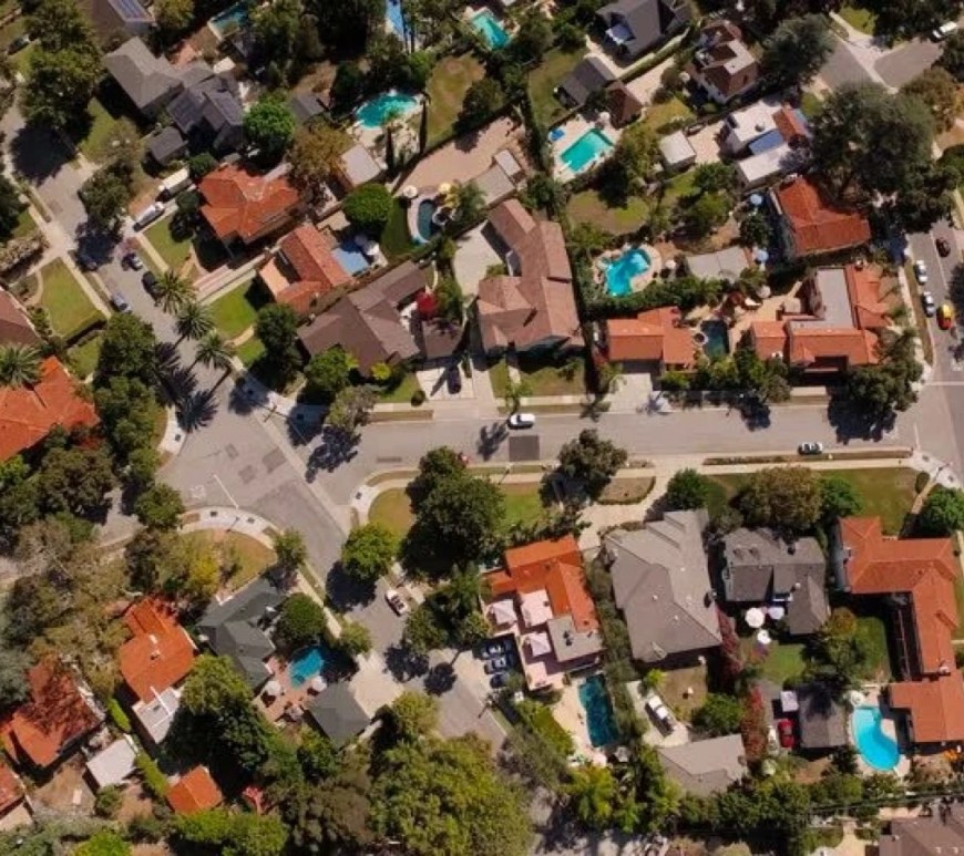 A quiet American suburban neighborhood with tree‑lined streets and rows of single‑family homes under soft daylight, representing the traditional image of the American Dream.