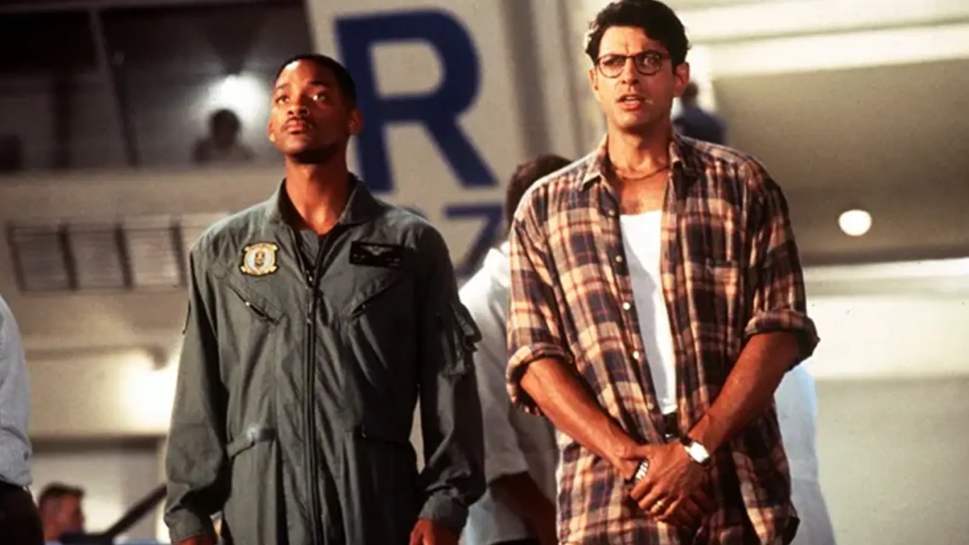 A movie still from Independence Day (1996) featuring the massive alien 'City Destroyer' spaceship hovering over the Empire State Building, symbolizing the film's $817 million global box office takeover.