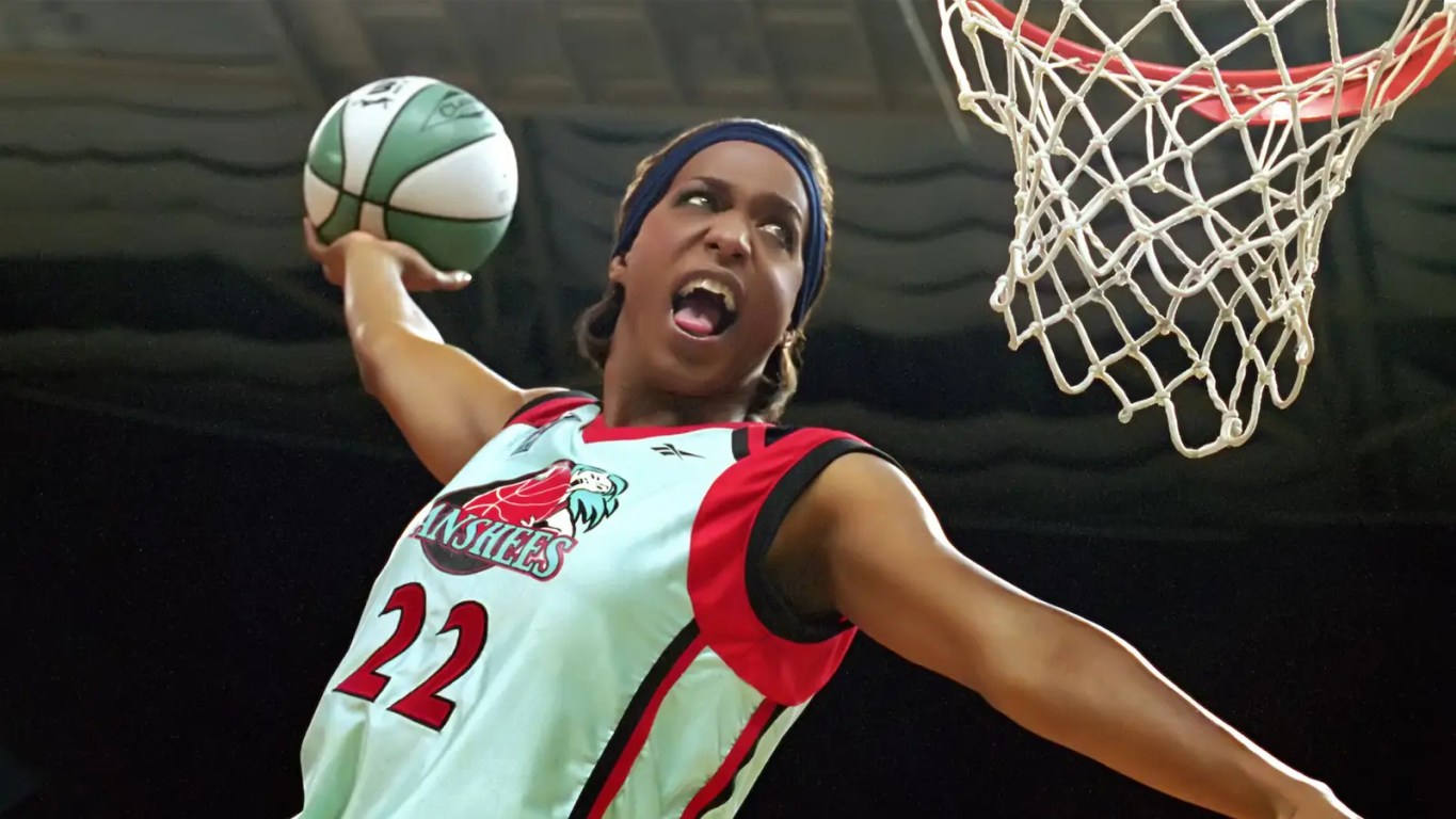 Miguel A. Núñez Jr. as Juwanna Mann on the basketball court in a teal and yellow Charlotte Banshees jersey, surrounded by early 2000s WNBA-style arena branding.