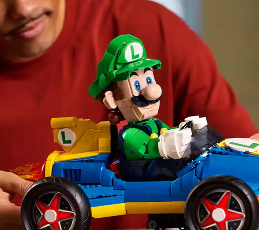 Detailed front profile look at the LEGO 72050 Luigi and Mach 8 Mario Kart. The 2,234-piece 1:8 scale model is pictured at a 30-degree drift angle on its custom display stand, highlighting the functional steering and mechanical flame exhaust.