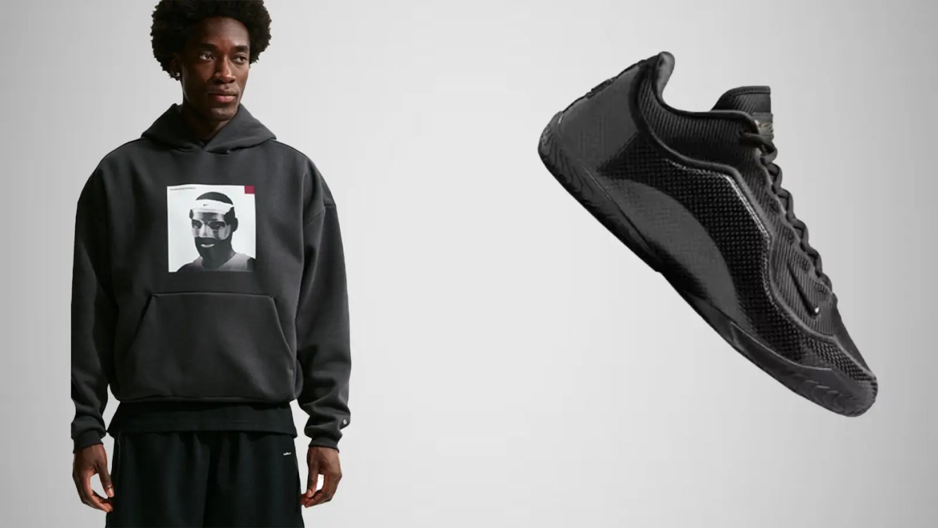 A side-profile view of the Nike LeBron 23 'Masked Menace' in an all-black colorway, featuring sleek, woven carbon fiber-style panels on the upper, a 3D-molded crown logo on the heel resembling a protective face mask, and a full-length black outsole