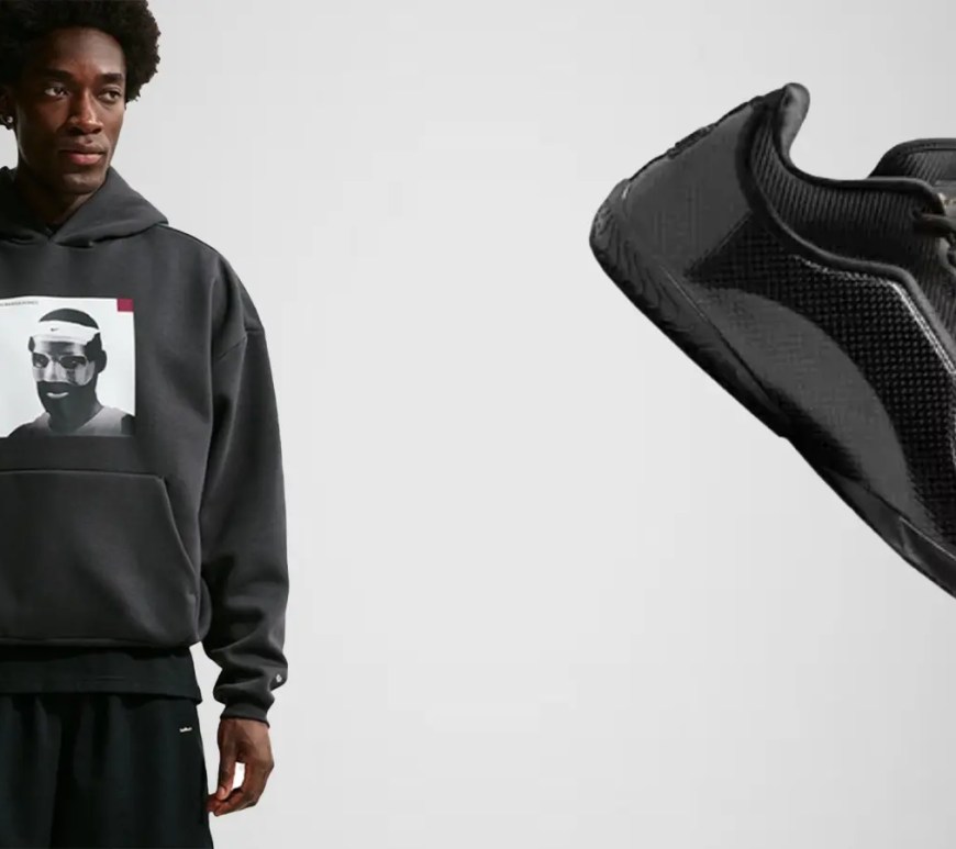 A side-profile view of the Nike LeBron 23 'Masked Menace' in an all-black colorway, featuring sleek, woven carbon fiber-style panels on the upper, a 3D-molded crown logo on the heel resembling a protective face mask, and a full-length black outsole