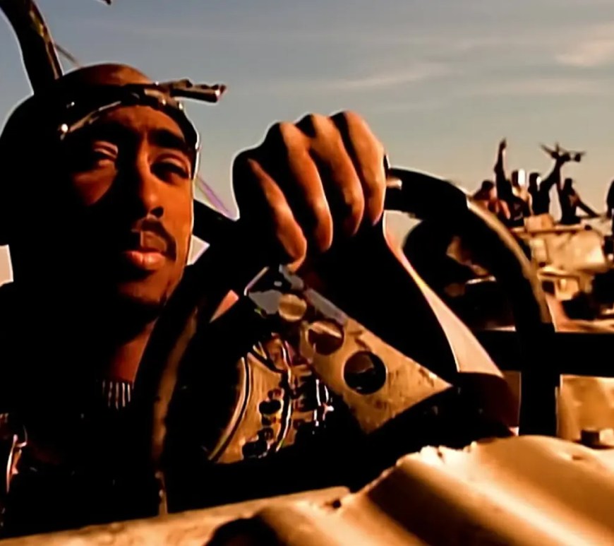 Tupac Shakur and Dr. Dre performing inside the custom steel 'Thunderdome' set in the El Mirage desert, showcasing the high-budget visual engineering of the California Love music video.