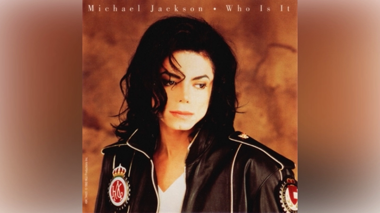 Is Who Is It Michael Jackson's greatest deep cut? Cover art for Michael Jackson’s single ‘Who Is It,’ showing him in a black leather jacket with metallic patches over a white shirt, set against a warm brown background with the title printed at the top.