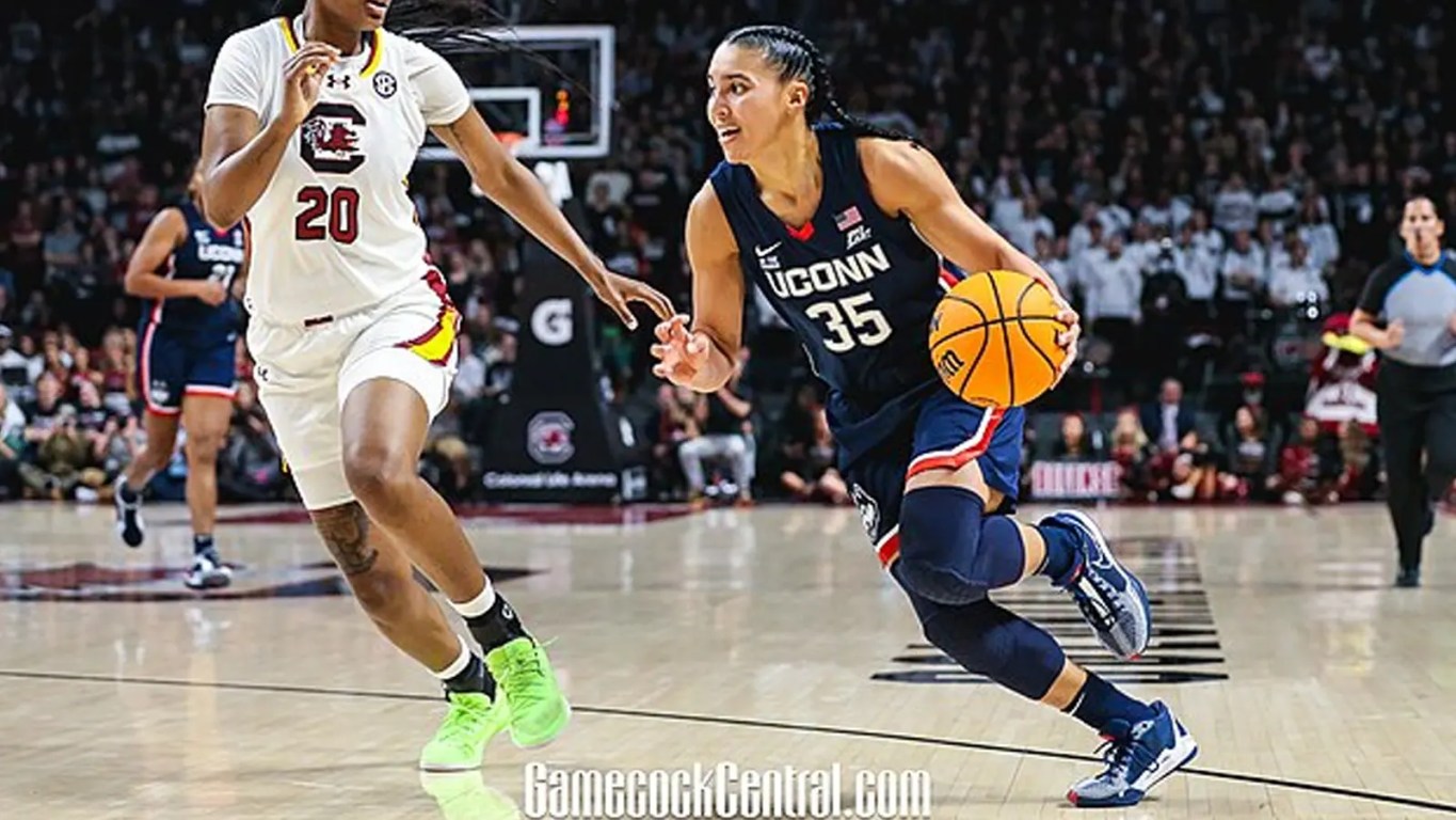 UConn star Azzi Fudd scanning the floor while dribbling up the court, highlighting the high-fidelity detail of her Nike basketball sneakers and the intensity of a top-tier collegiate matchup.