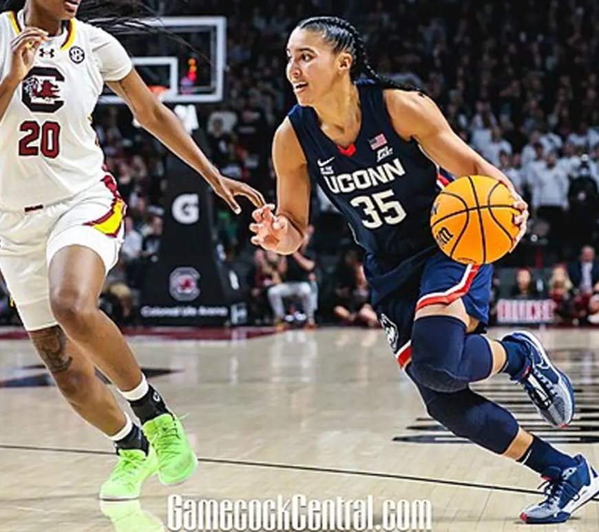 UConn star Azzi Fudd scanning the floor while dribbling up the court, highlighting the high-fidelity detail of her Nike basketball sneakers and the intensity of a top-tier collegiate matchup.