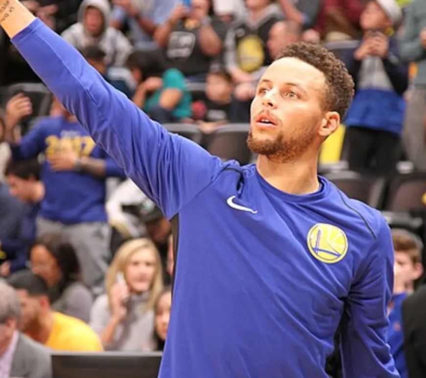 Steph Curry shooting a three-pointer at the Oracle Arena, capturing the high-stakes energy of the Warriors' elimination game.