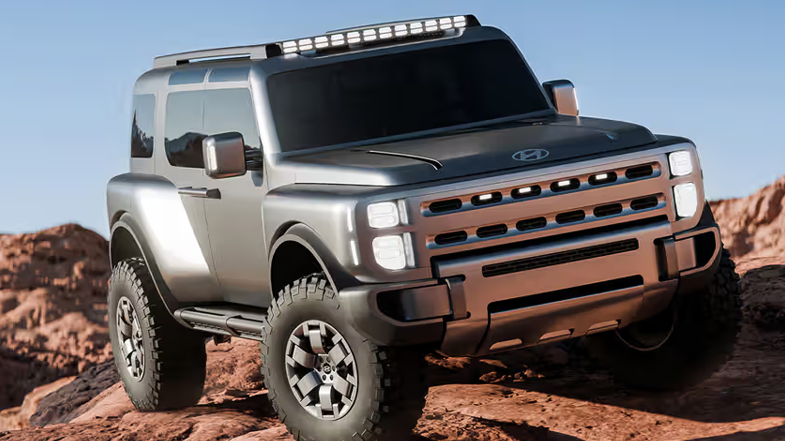 A front three-quarter view of the Hyundai Boulder Concept SUV in Liquid Titanium finish at the 2026 New York Auto Show. The vehicle features a boxy "Art of Steel" design, massive 37-inch mud-terrain tires, roof-mounted safari windows, and a low-profile steel-webbing roof rack, positioned as a rugged body-on-frame competitor to the Ford Bronco.