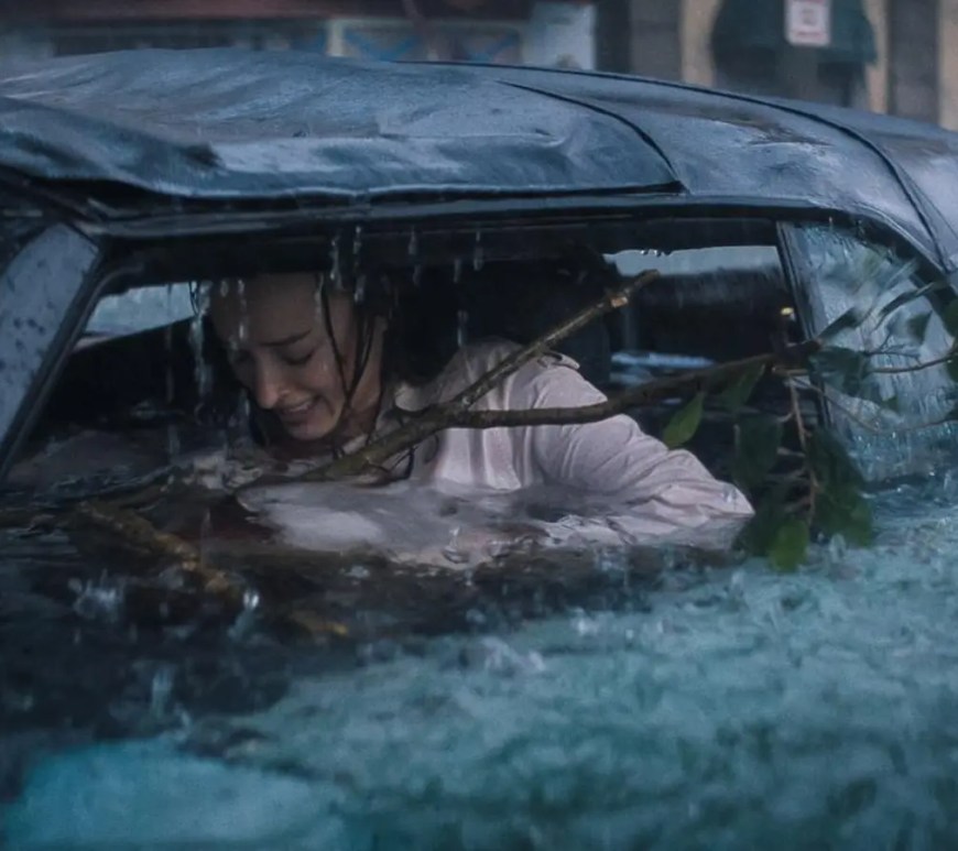 hoebe Dynevor as Lisa in the Netflix movie Thrash, appearing bloodied and determined while trapped in a flooded vehicle.