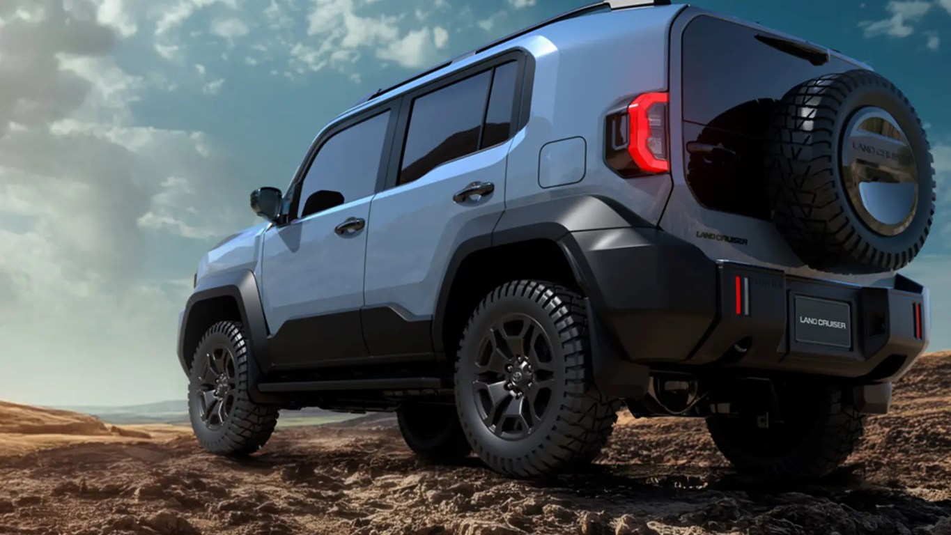 The 2026 Toyota Land Cruiser FJ in Heritage Blue, showing the retro boxy silhouette and round LED headlights in an off-road mountain setting.