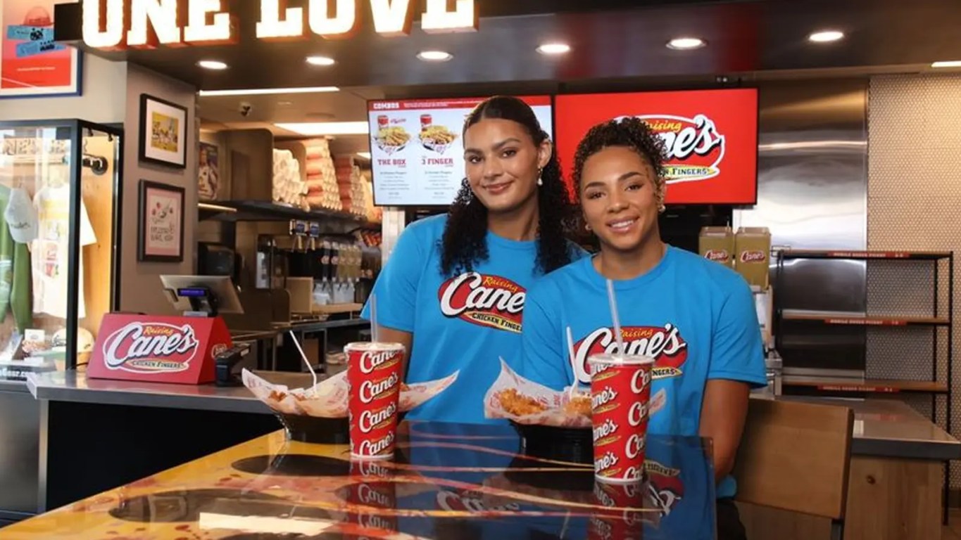Lauren Betts and Kiki Rice in Raising Cane’s uniforms holding a Box Combo and a basketball in Hollywood.