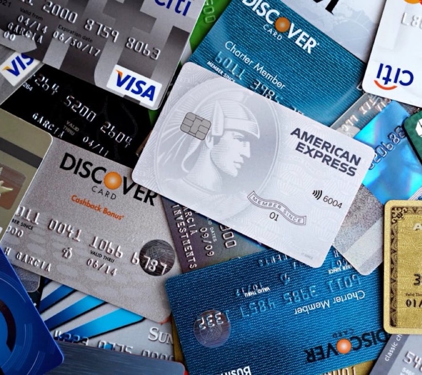 Credit Crisis: Assorted credit cards from major issuers including Visa, Mastercard, American Express, Discover, Chase, and Citi scattered across a surface, illustrating consumer debt and financial stress.