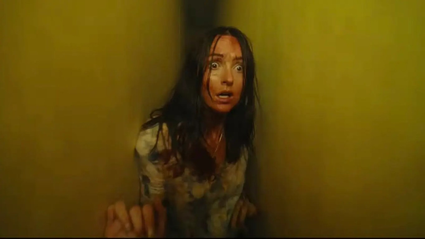 A tense, high-contrast close-up film still of Mary (Renate Reinsve) looking terrified inside a dimly lit fluorescent corridor in the movie Backrooms.