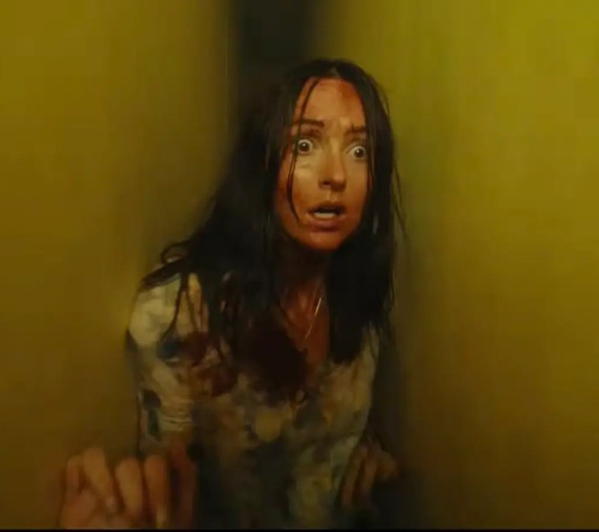 A tense, high-contrast close-up film still of Mary (Renate Reinsve) looking terrified inside a dimly lit fluorescent corridor in the movie Backrooms.