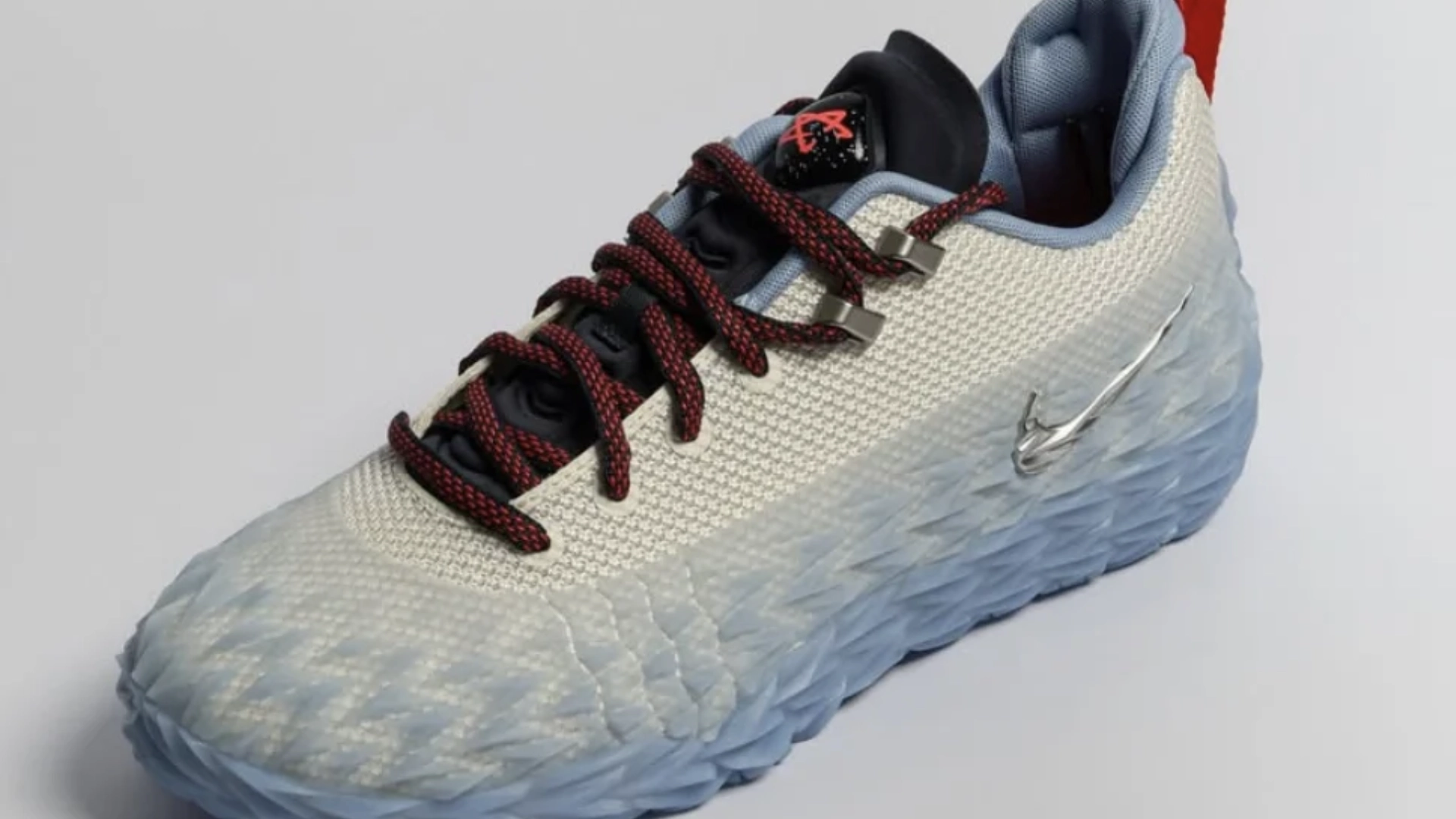 Side profile of the Nike ST Charge Cade Cunningham Detroit Tough sneaker, featuring a white reinforced mesh upper encased in a geometric, icy translucent blue TPU armor overlay that spans from the toe box to the heel, accented by a metallic silver Swoosh on the midsole and custom red and blue athletic laces.