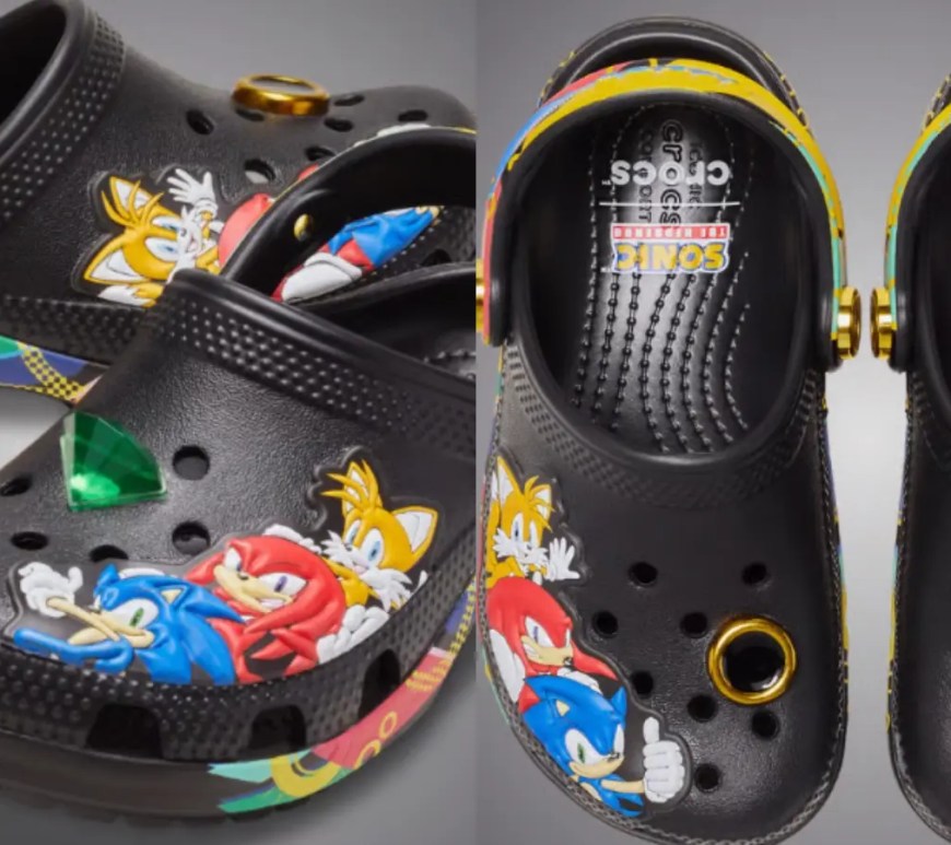 A front and side profile of the special-edition Sonic the Hedgehog Crocs Classic Clog, highlighting the all-over multi-color pixel print of gold rings stretching across the midsole and the adjustable sport-mode heel strap.