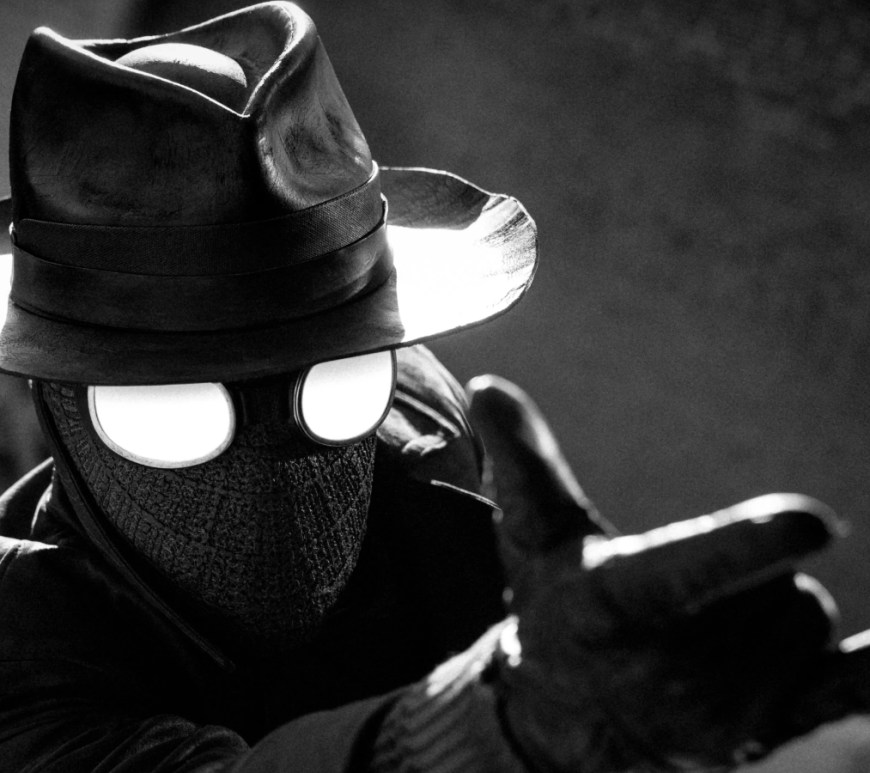 Front profile of Nicolas Cage as Ben Reilly in the live-action Spider-Noir series, wearing a classic 1930s fedora and a dark wool trench coat.