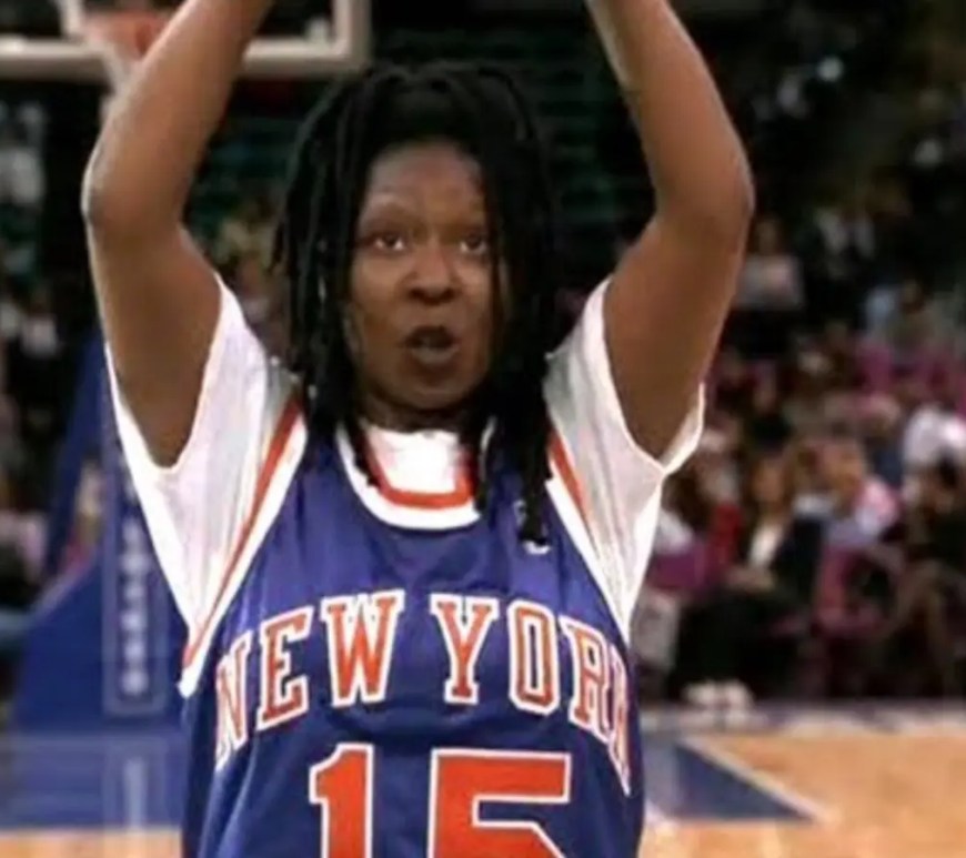 A vibrant horizontal production still from 1996 showcasing Whoopi Goldberg standing on a polished basketball court hardwood floor.