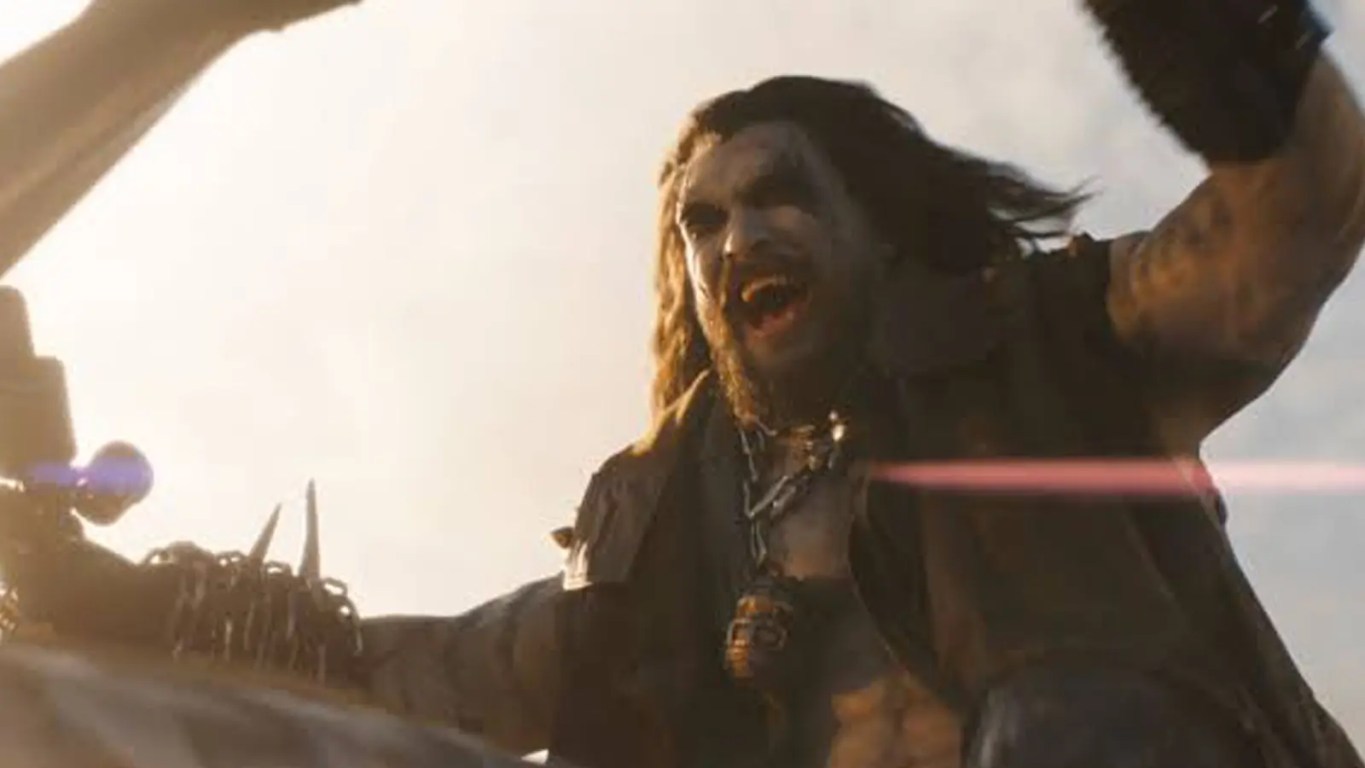 A dark, atmospheric cinematic movie still of Jason Momoa transformed into the DC character Lobo, featuring chalk-white skin, long chaotic black hair, and glowing red eyes