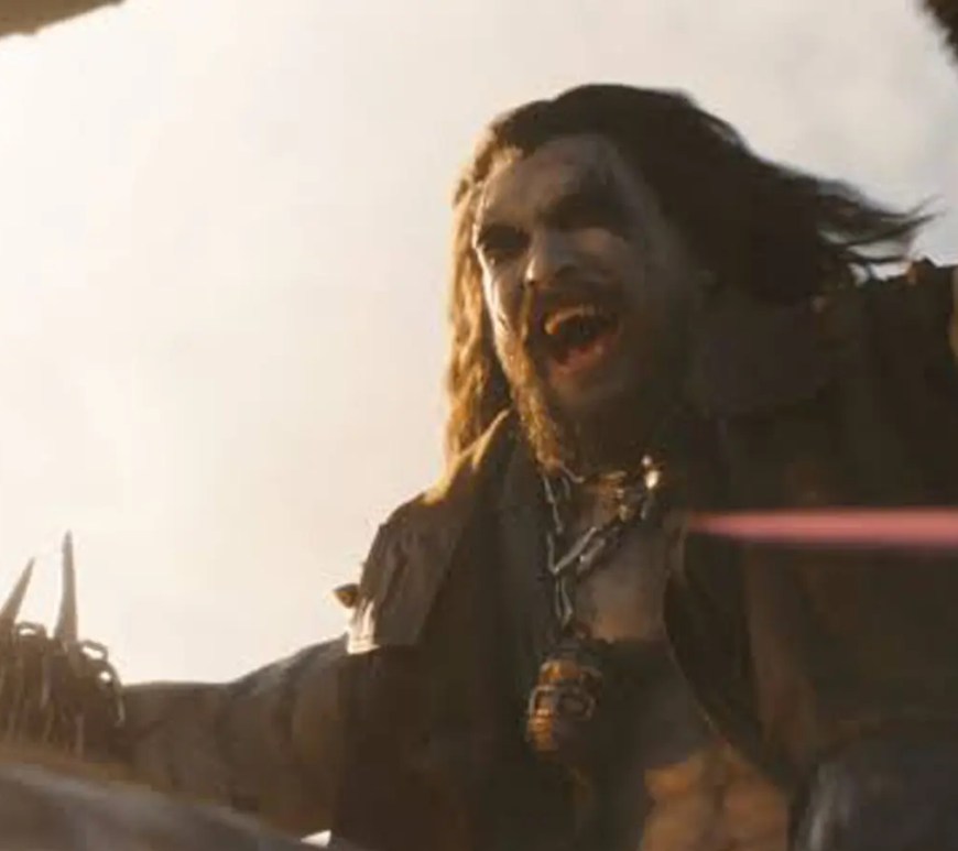 A dark, atmospheric cinematic movie still of Jason Momoa transformed into the DC character Lobo, featuring chalk-white skin, long chaotic black hair, and glowing red eyes