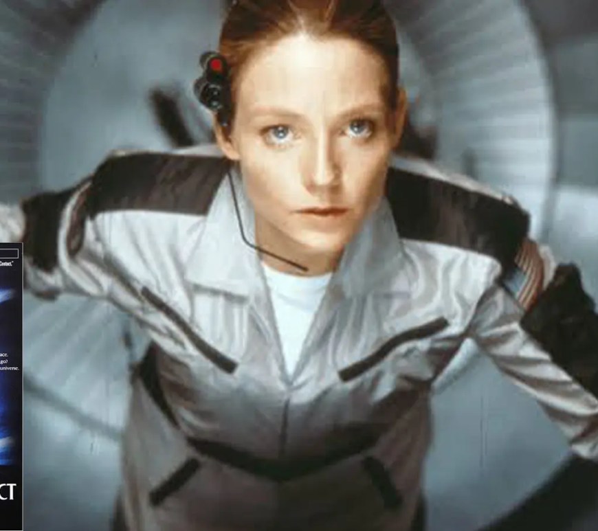 A dramatic, wide cinematic film still from the 1997 movie Contact, showing Jodie Foster standing in front of the massive, sweeping metallic radio telescopes of the Very Large Array.