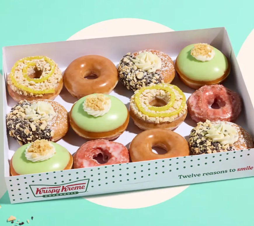 A bright, high-quality product photograph showcasing the new Krispy Kreme Summer Seasonal Collection arranged neatly on a countertop,