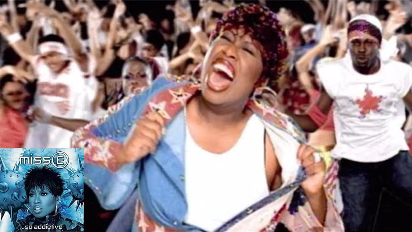 A high-contrast, atmospheric music video film still from Missy Elliott's 2001 single Take Away, showcasing her performance layout under neo-noir urban staging lights.