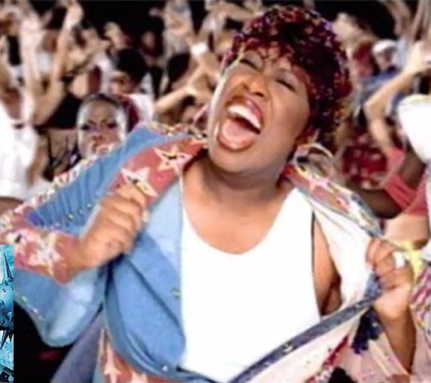 A high-contrast, atmospheric music video film still from Missy Elliott's 2001 single Take Away, showcasing her performance layout under neo-noir urban staging lights.