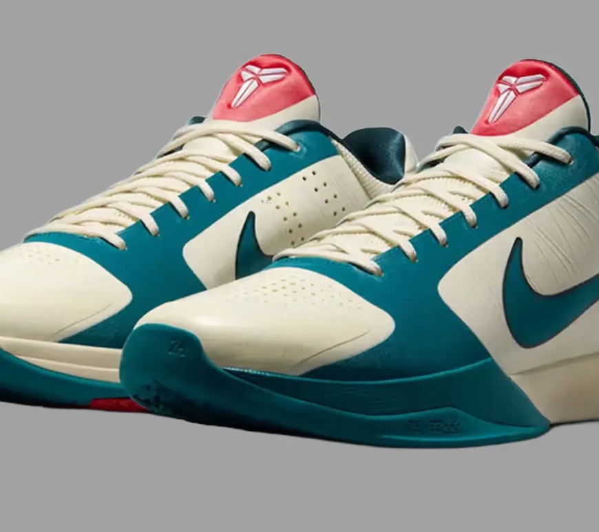 A clean, high-contrast studio front profile shot of the Caitlin Clark x Nike Kobe 5 Protro Scrabble, highlighting the smooth Coconut Milk upper, a vibrant Bright Spruce green Swoosh, and subtle University Red accents on the outsole against a grey background.