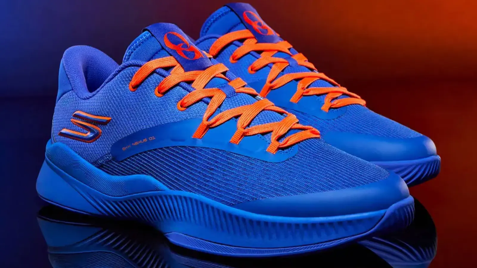 A detailed lifestyle profile shot of a low-top blue and orange performance basketball shoe highlighting the mesh upper pattern and customized interior player branding.