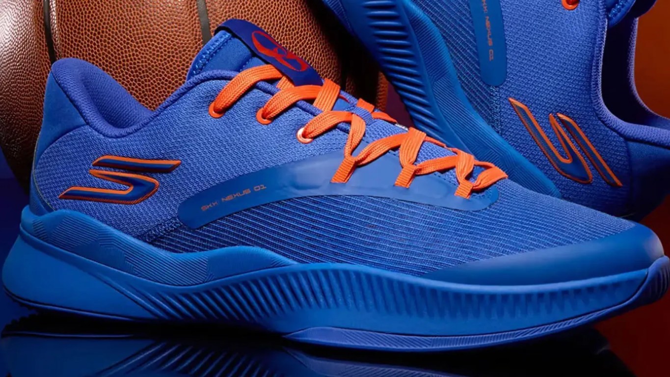 A detailed lifestyle profile shot of a low-top blue and orange performance basketball shoe highlighting the mesh upper pattern and customized interior player branding.