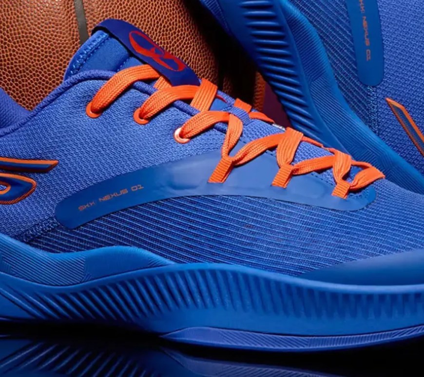 A detailed lifestyle profile shot of a low-top blue and orange performance basketball shoe highlighting the mesh upper pattern and customized interior player branding.