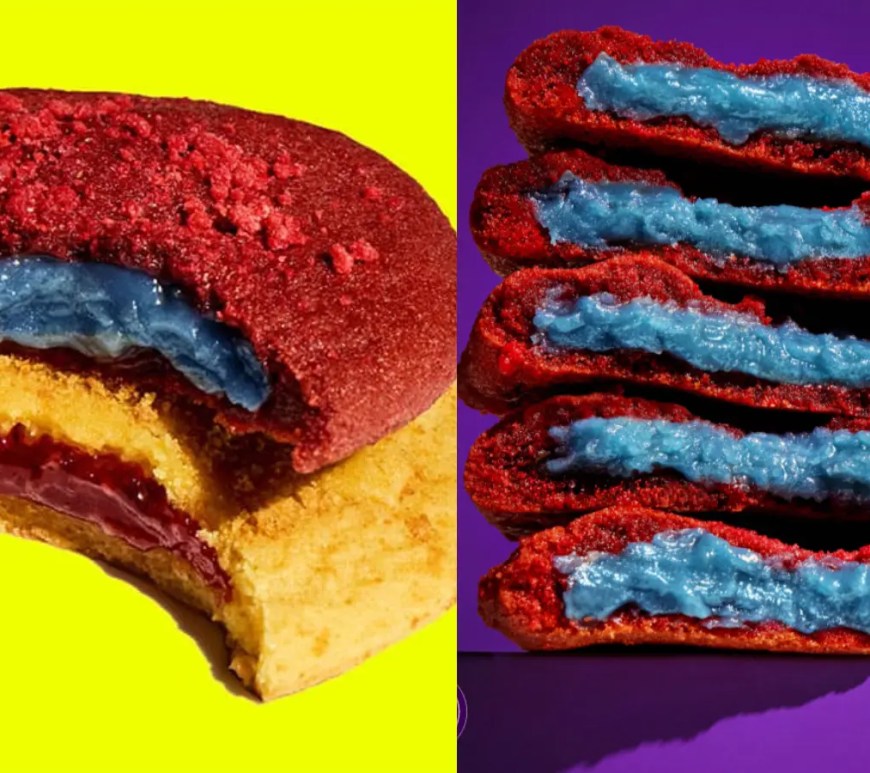 A wide close-up display showcasing promotional Insomnia Cookies packaging styled with vibrant Supergirl branding and custom movie artwork alongside newly released red velvet and lemon cookies.