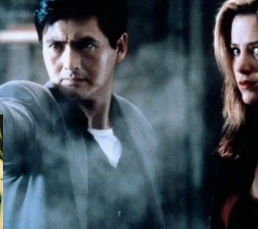 A high-contrast neon noir action still from the 1998 film The Replacement Killers, showing Chow Yun-Fat and Mira Sorvino in a dual-weapon tactical combat sequence.