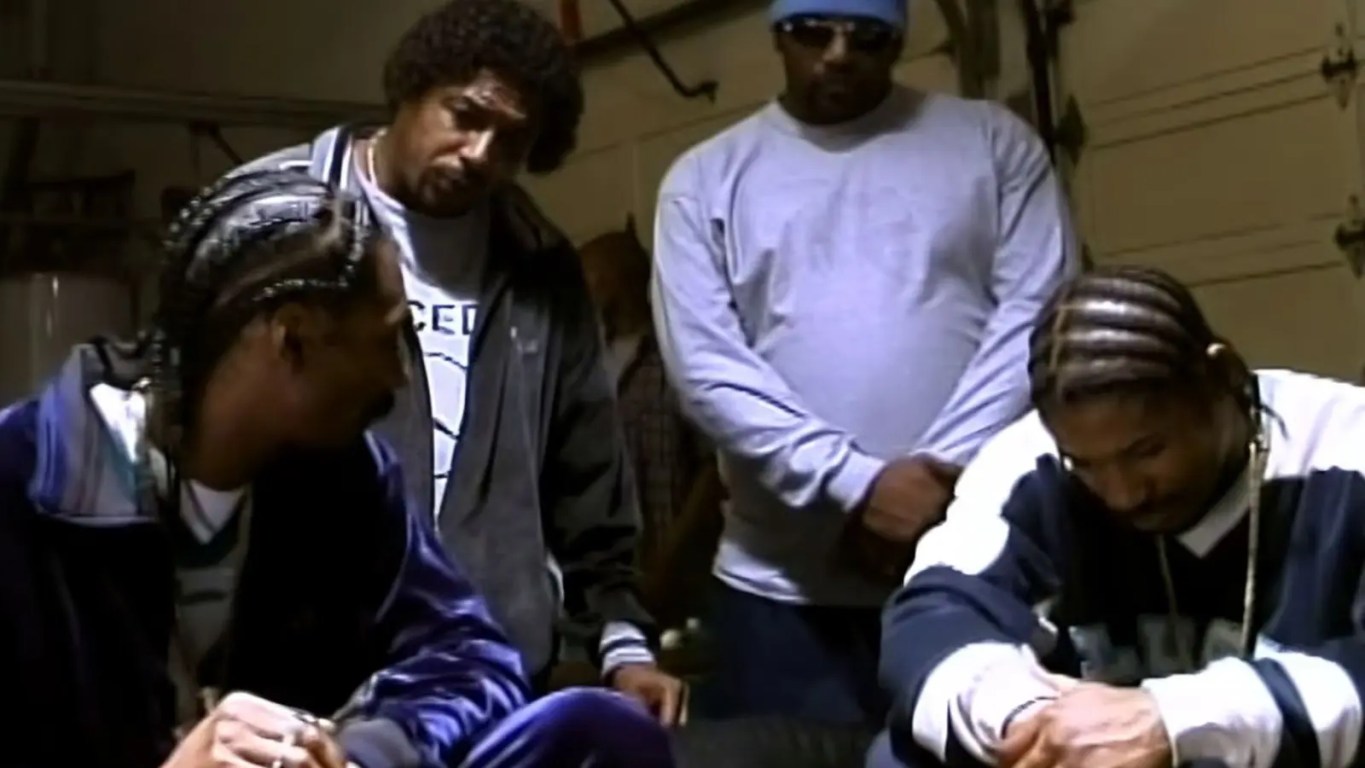 A horizontal vintage promotional group photograph from 2000 featuring Snoop Dogg, Tray Deee, and Goldie Loc dressed in classic blue LBC streetwear styling against a clean studio backdrop.